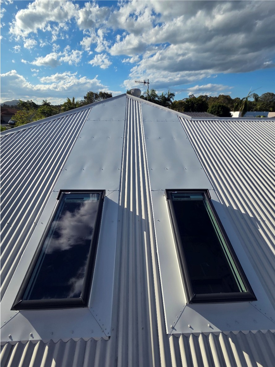 Two skylights installed either side of the ridge on a white metal roof.