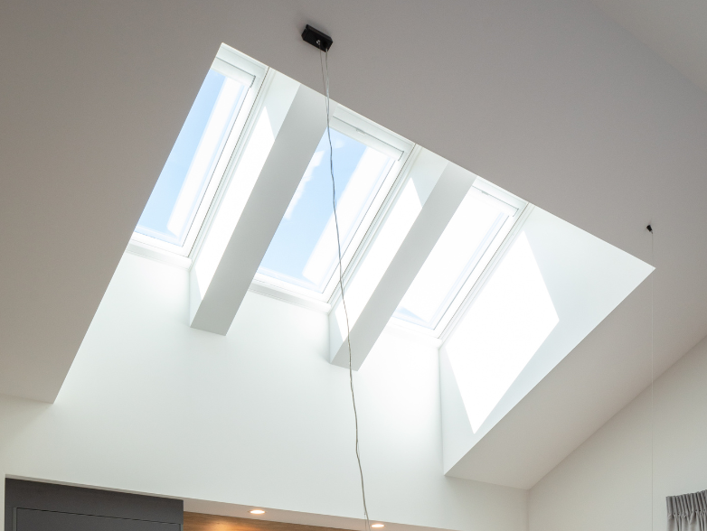 A triple skylight cluster set into a clean plaster ceiling above a finished room