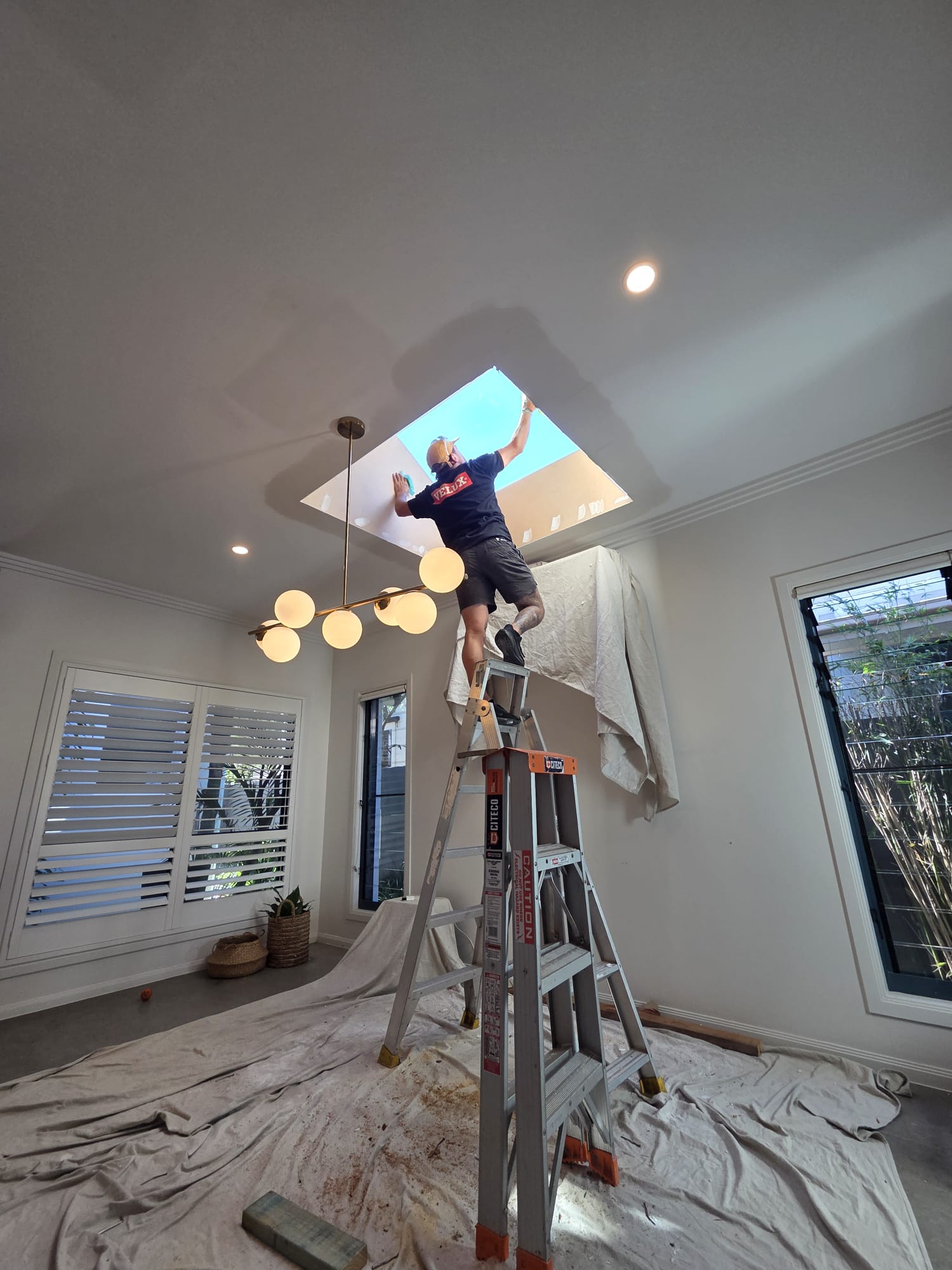 Installer finishing a new skylight opening from inside a home.