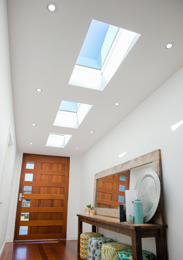 A hallway ceiling with skylights carrying daylight along the entry path