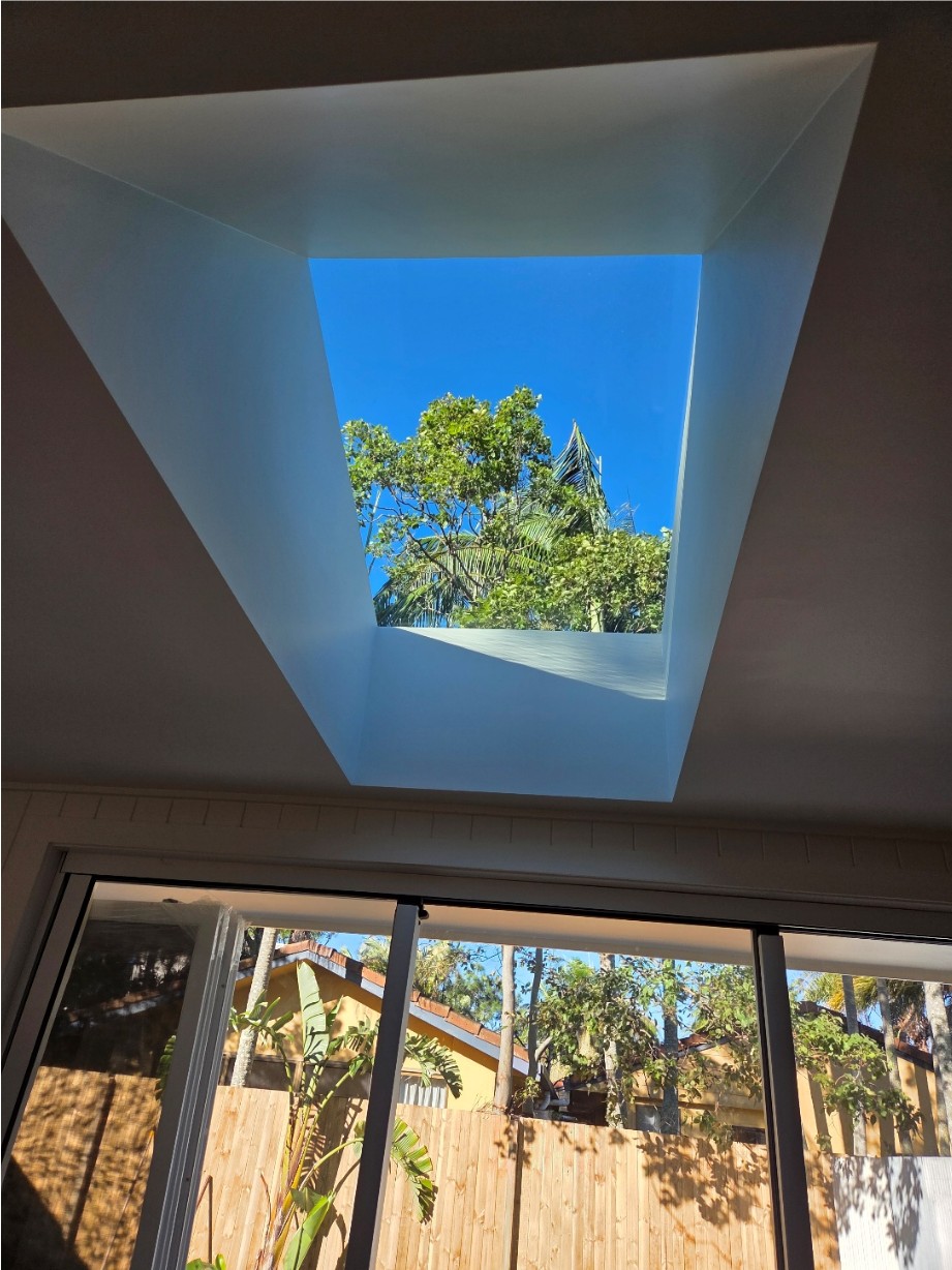 Large square skylight shaft looking up to trees and open sky.