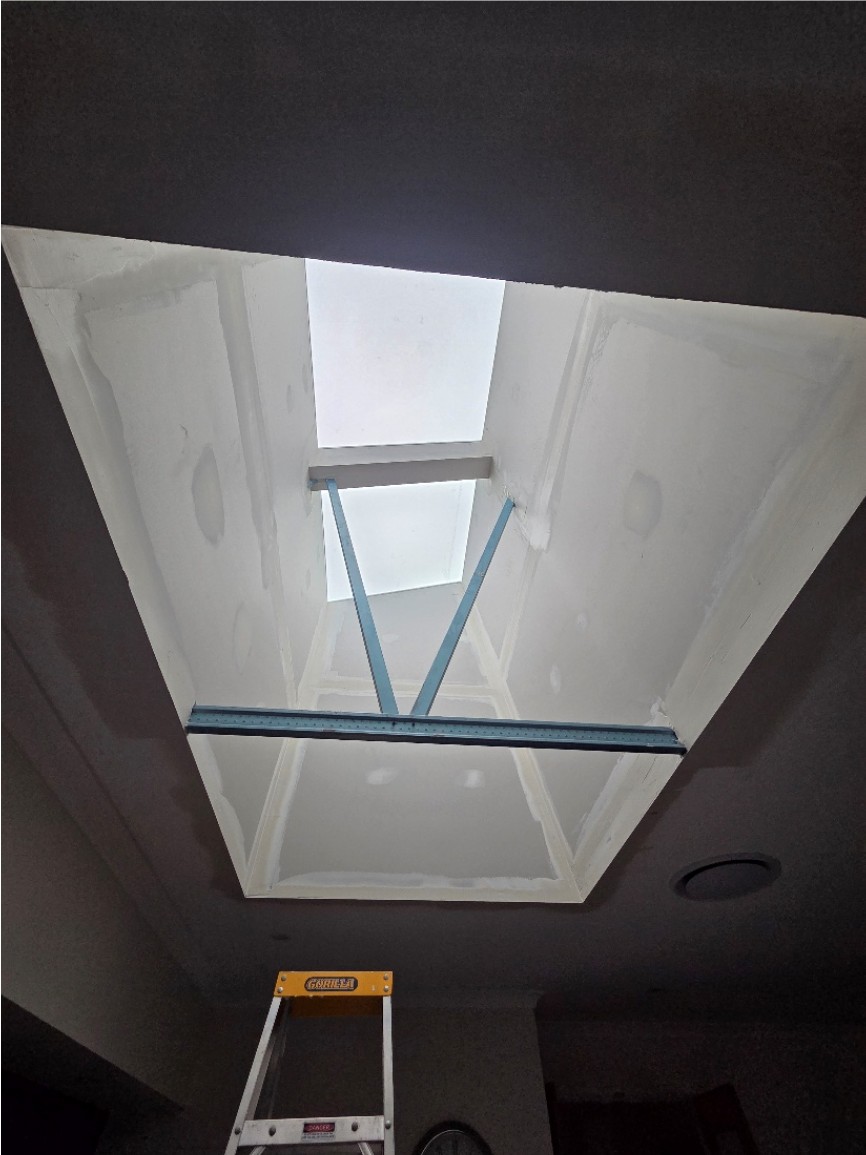 Skylight shaft with fresh plaster and a temporary brace, photographed during installation.